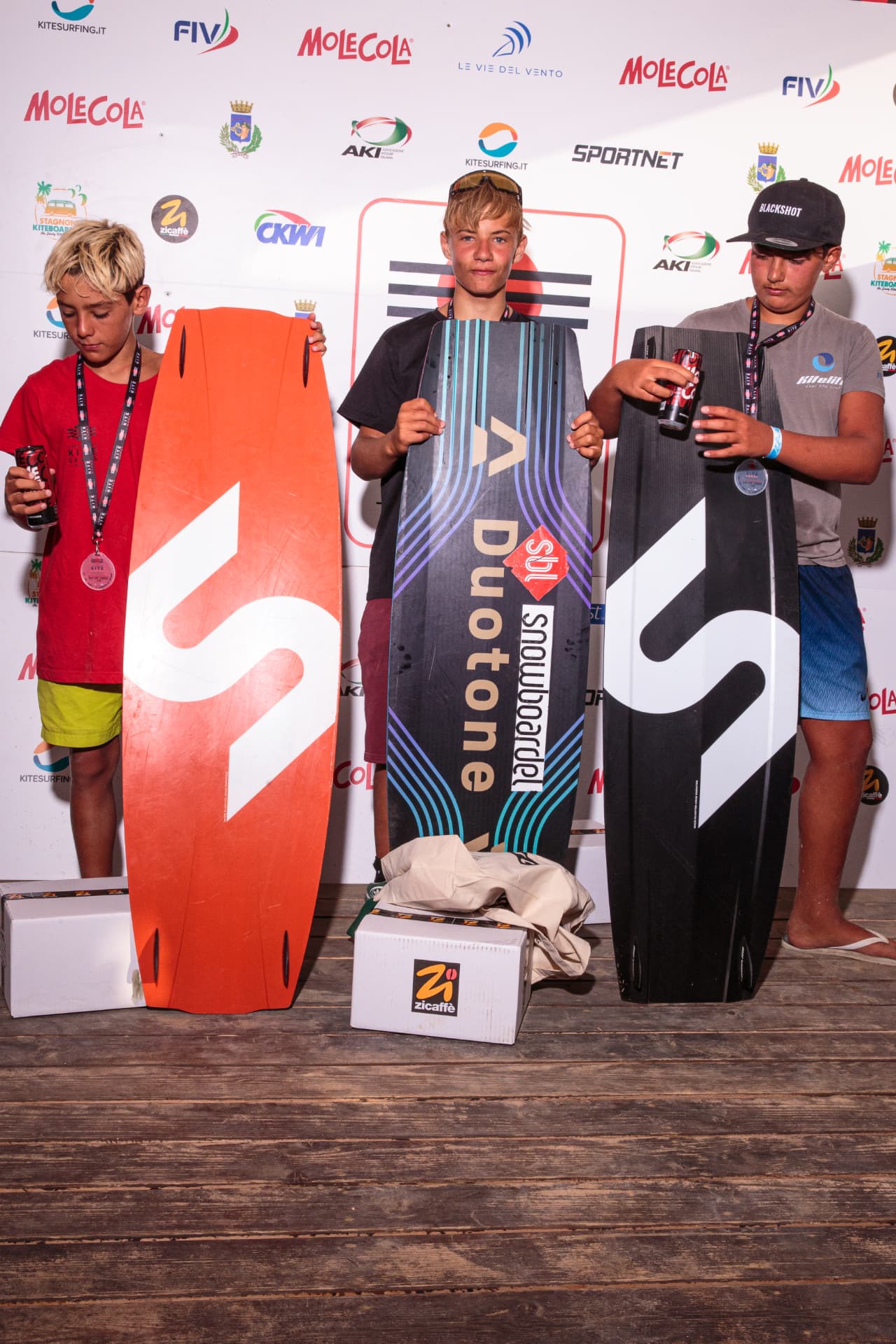 Atleti sul palco con tavole premio e trofei — premiazione Stagnone Kite Games 2026