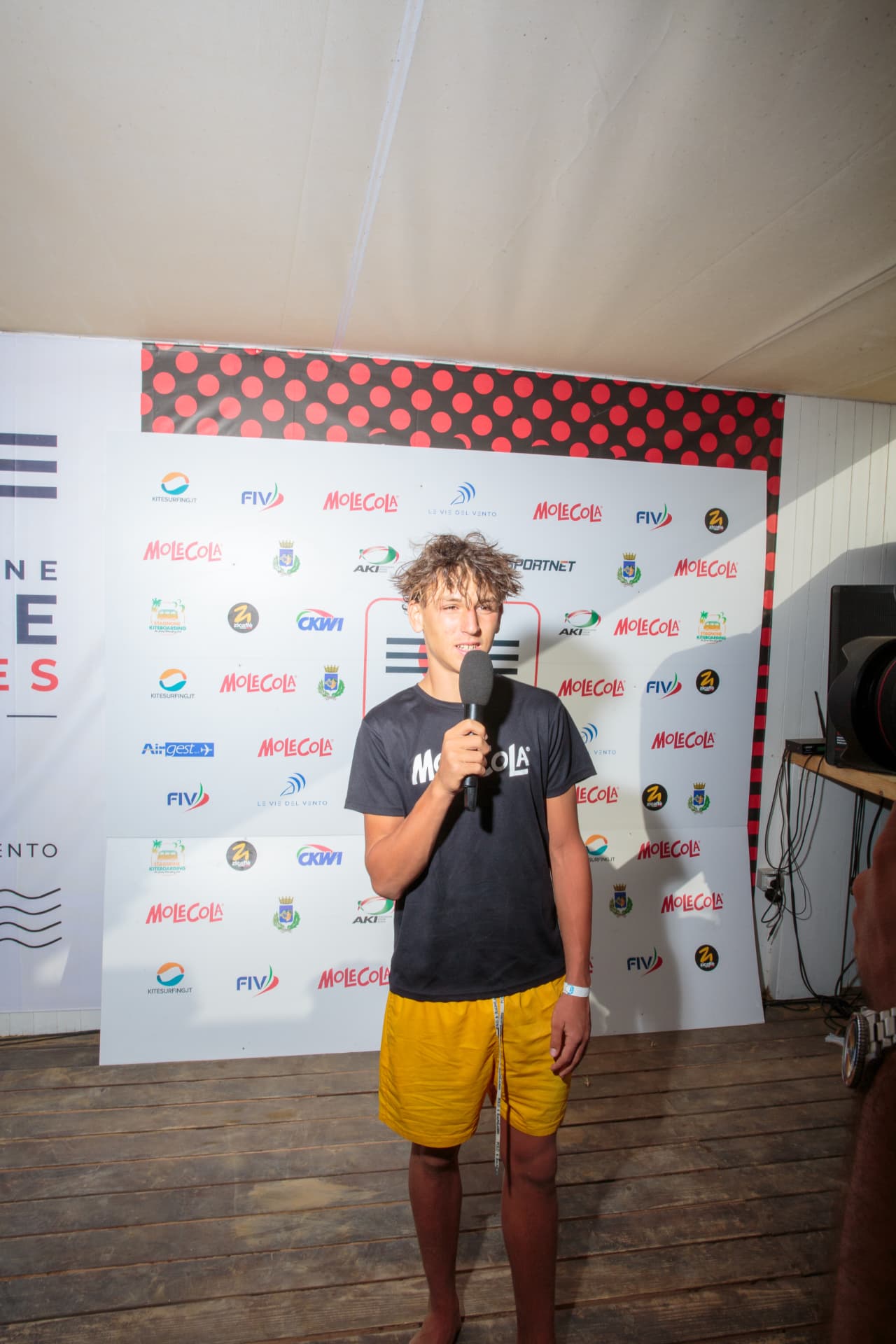 Giovane atleta intervistato davanti al backdrop 2026
